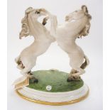 A Capo di Monte porcelain equestrian group: of two rearing horses, on an oval base, 33cm. high.