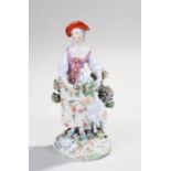 Porcelain figure, of a lady with a red hat holding a standing sheep with flowers, 21.5cm high