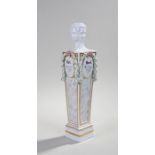 Meissen porcelain column, the column surmounted by a four portrait head above ribbon tied leaf