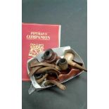 Seven smokers pipes and a wooden pipe holder, together with a book, The Pipeman's Companion, (Qty)