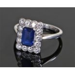 Platinum sapphire and diamond ring, the central emerald cut sapphire with fourteen round cut