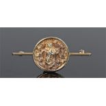 Yellow metal Eastern brooch, with a deity to the circular brooch mounted to a bar brooch setting,