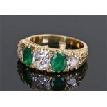 Emerald and diamond ring, the central diamond at approximately 0.8 carat flanked by two oval