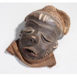 African Pende mask, Congo, with a straw top above the deep eye lids, long nose and open mouth with