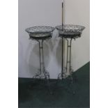 Two grey painted wrought iron plant stands, with pierced basket form top sections, on scroll