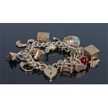 9 carat gold charm bracelet, with a selection of charms to include medallions, a cased note, a