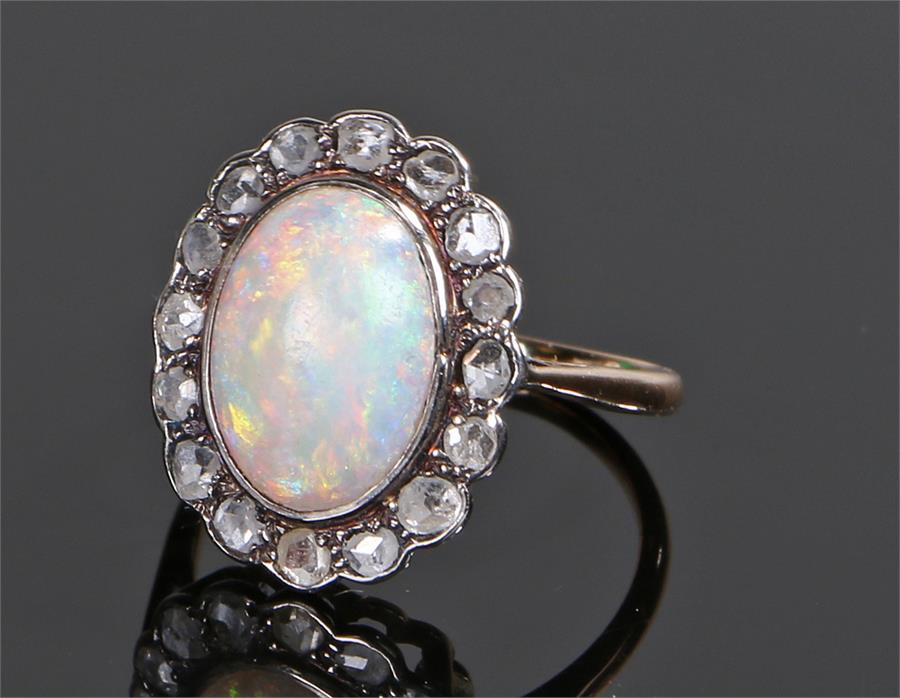 18 carat gold opal and diamond ring, the central oval cabochon opal with a diamond surround, ring