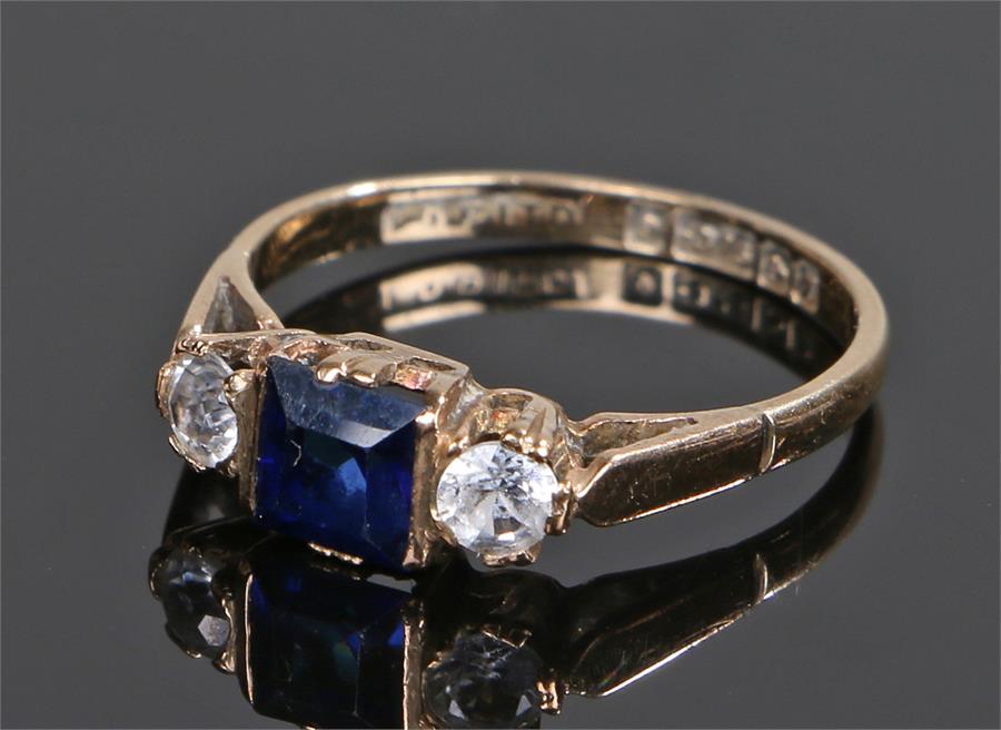 9 carat gold sapphire set ring, the central emerald cut sapphire flanked by cubic zirconia, ring