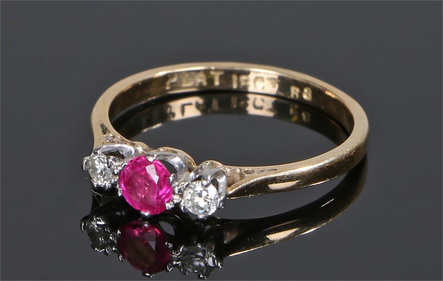 18 carat gold ruby and diamond ring, the central ruby flanked by a diamond to either shoulder,