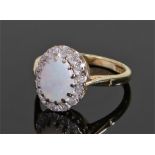 18 carat gold opal and diamond set ring, the oval opal with a diamond surround, ring size N