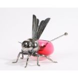 Silver plated honey pot in the shape of a bee with red glass body, the wings over the opening with