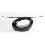 Glass coffee table, the oval top on a Barbara Hepworth style pierced black plastic loaded base,