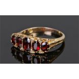 18 carat gold garnet set ring, with a row of five garnets to the head, ring size S