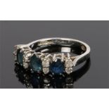 9 carat white gold sapphire and diamond ring, the head set with three oval sapphires and eight round