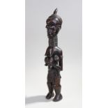 African Luba figure, carved with a long neck clutching a baby near the naked top half, 53cm high