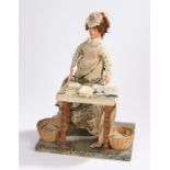 Doll set, to include a doll of a lady by her work table with an iron and various materials, the doll