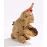 Early 20th Century wind up monkey, with a red hat above an arched body and a cymbal to each hand,