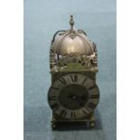 20th century lantern clock, the bell top above dolphin panels and the circular dial with Roman