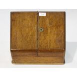 Oak desktop stationery box, the sloping front opening to reveal a pigeonholed interior with pen tray