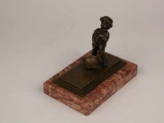 Kleine Bronzefigur - Knabe beim Wasserlassen, mit runder Schüssel, auf rechteckiger Plinthe und
