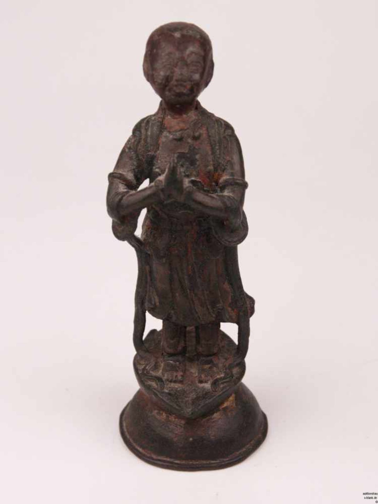 Kleine Arhat-Figur - Bronze, Lack-und Vergoldungsreste, stehend auf hoch gewölbtem Sockel, die Hände