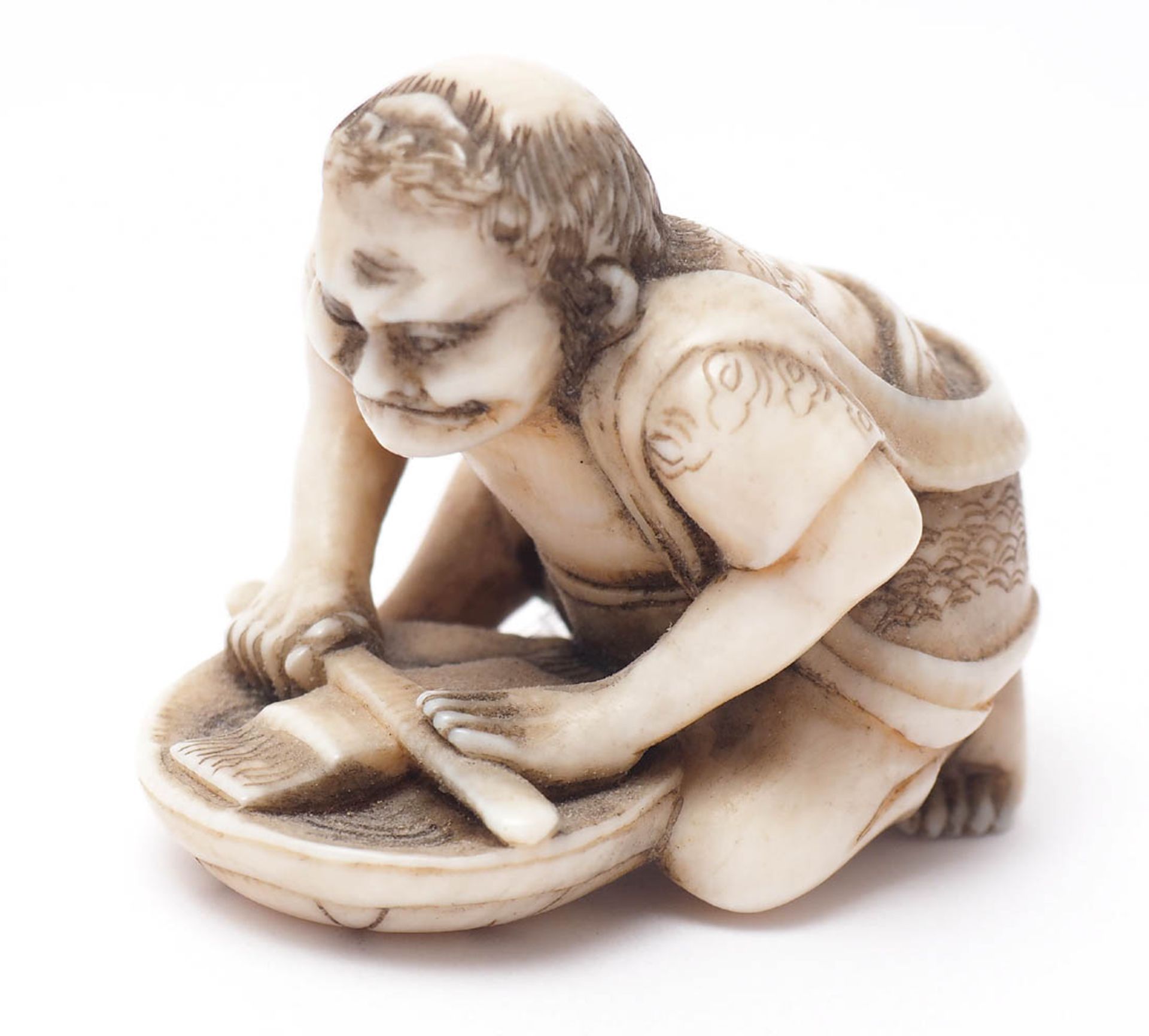 Netsuke, 19.Jhdt. Feine Schnitzerei. Hockender Mann, seinen Säbel schleifend. Altersgebräuntes