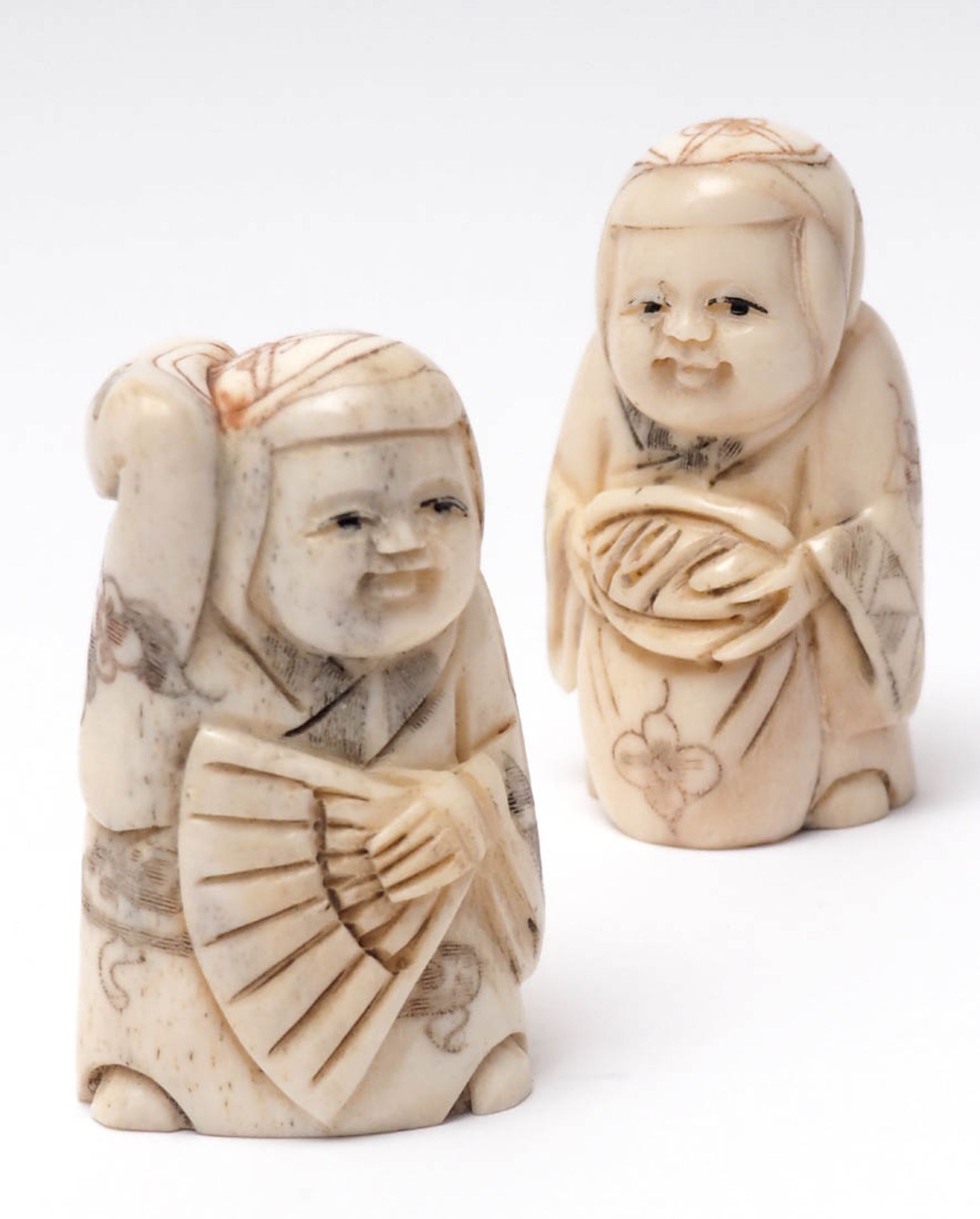 Zwei Netsuke, Japan In Form einer Frau mit Fächer bzw. einer Bauersfrau mit Brot. Elfenbein, auf dem