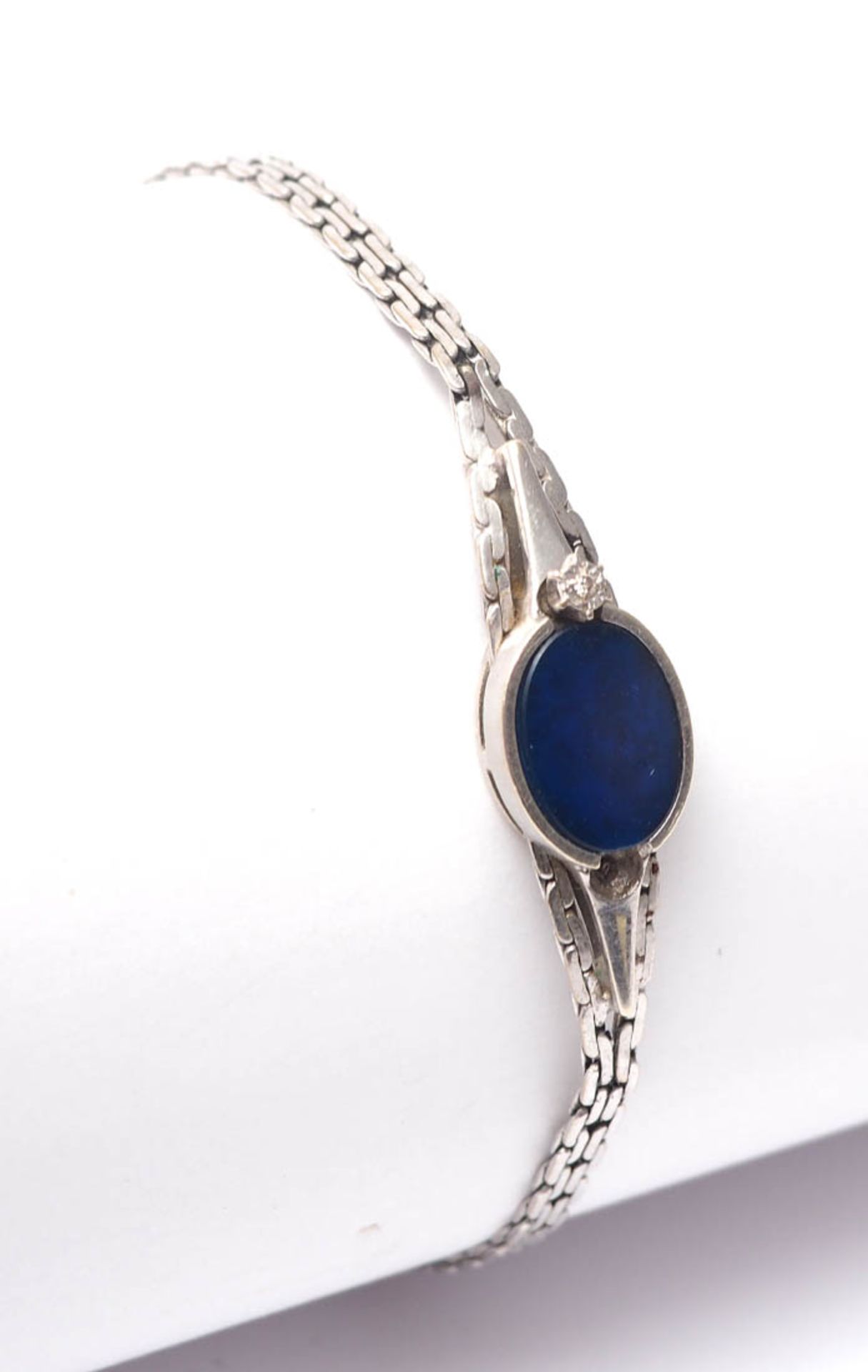 Armband WG 8kt. Mittig ovaler Lapislazuli, flankiert von Punktdiamanten (einer fehlt). L.20cm,