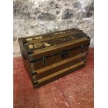 A wooden bound, dome top travel trunk