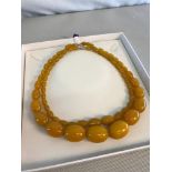 2 Butterscotch Bakelite Graduating Amber beads with yellow metal clasps.