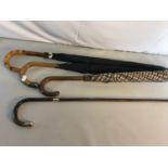 A collection of umbrellas and walking stick which includes silver collard walking stick and umbrella