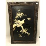 An oriental piece of art depicting a bird scene in mother of pearl and bone, completed on a panel