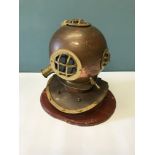 A reproduction brass & copper divers helmet fitted upon a display stand