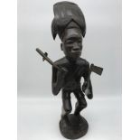 Carved Ebony African tribal figure. Holding axe, tool and has a sword. Stands 33cm in height