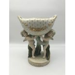 A Victorian porcelain figure. Cherubs holding a basket. Measures 23cm in height