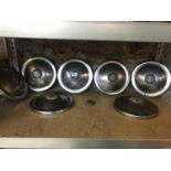 Seven vintage MG hub caps in chrome with one spare MG logo. Diameter 22cm