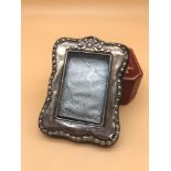 A Chester silver photo frame styled with ribbon top and edging. Makers James Deacon & Sons.