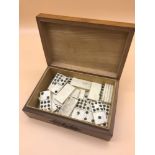 A antique carved box filled with antique bone dominos
