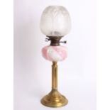 A Victorian paraffin lamp with a brass column, a white and pink glass reservoir and a etched glass