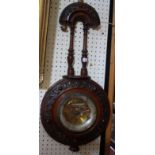 A late Victorian aneroid barometer in a fancy carved mahogany case and partly coloured dial,