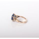 A synthetic sapphire round single stone ring stamped '18K'