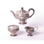 A late Victorian silver small three piece round pedestal tea service, each profusely embossed with