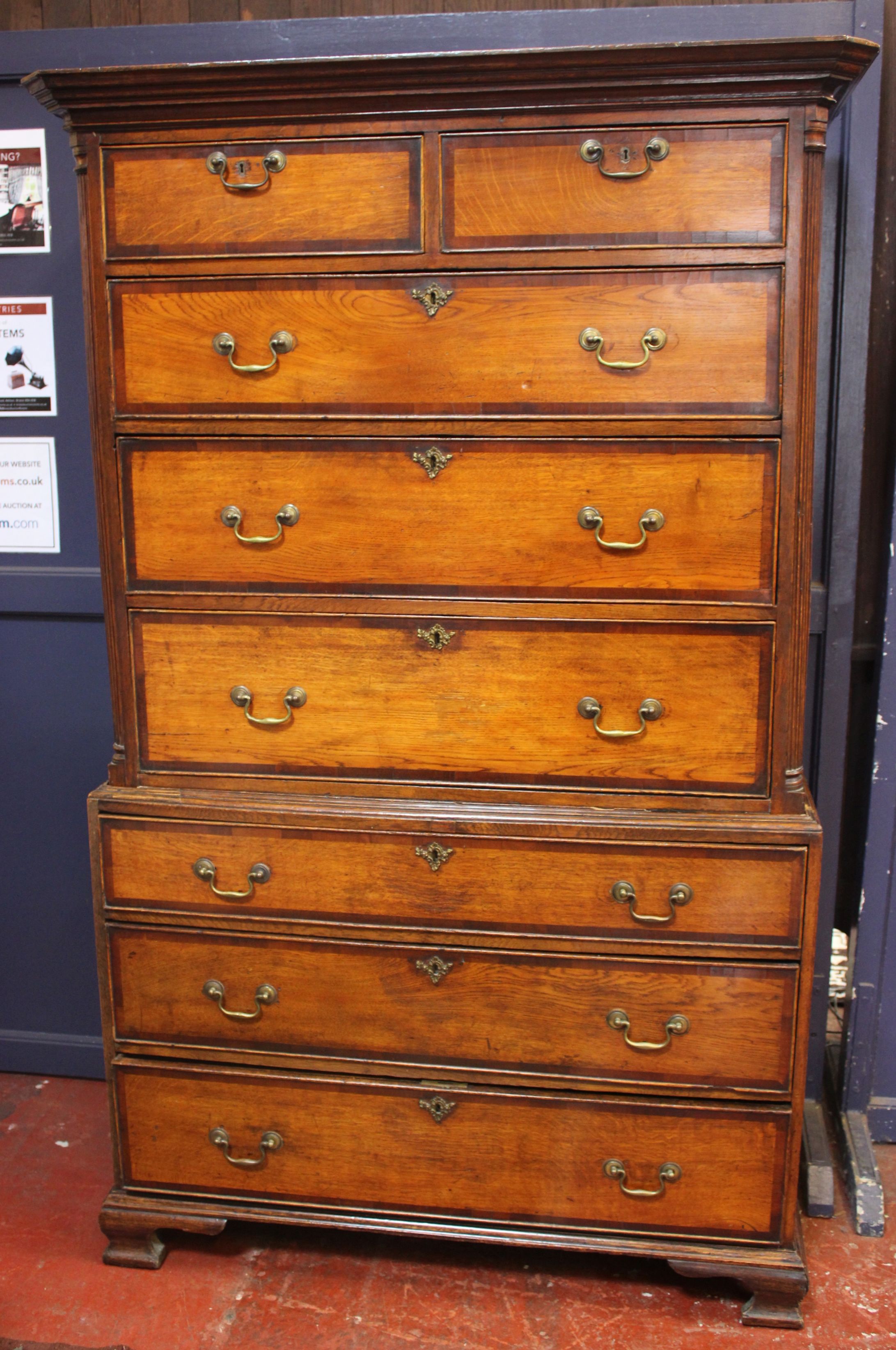 A George III stained oak chest on chest of two short and six long drawers with mahogany crossbanding