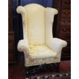 An early 18th century style high wing back armchair with carved front stretcher, recently re-