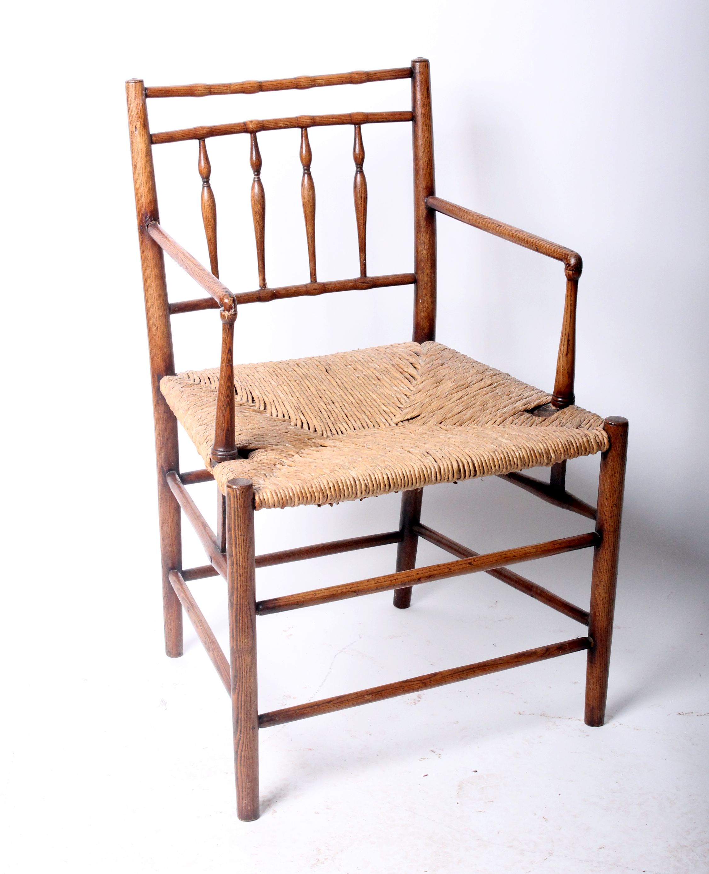 An Arts and Crafts beech delicate spindle back open arm chair with woven rush seat w.57cm