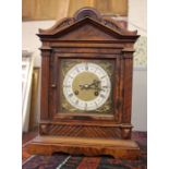 An Edwardian mantel clock with brass face and gong striking movement with key and pendulum in walnut