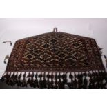 A late 19th/early 20th Century Turkoman pentagonal bag face with a woven border and woollen tassels,