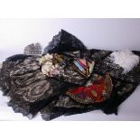 A black lace cape; a floss silk embroidered motif, silk threads, a floral headdress, white Ostrich