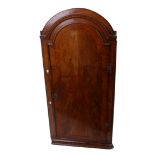 An 18th Century walnut corner cupboard with an arched top enclosing shelves 139cm high, 68cm wide