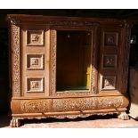 A Renaissance style oak carved and glazed cabinet three cupboards, the central cupboard glazed, with